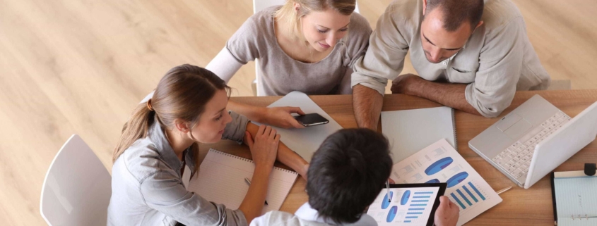 Four employees working together around a desk