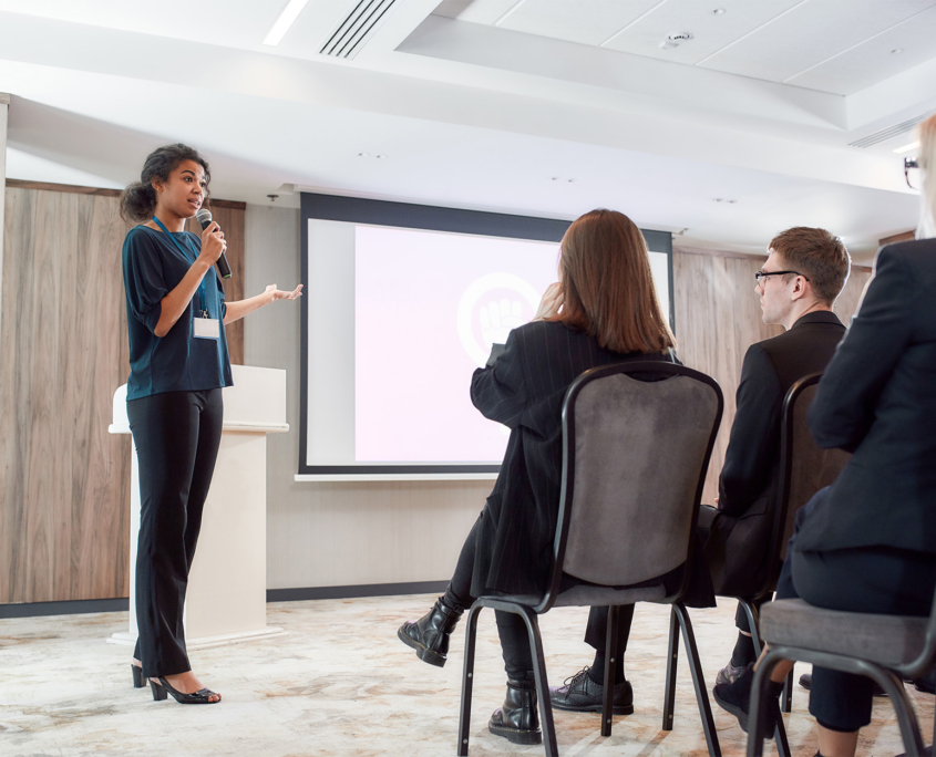 Side View Of Female Speaker Talking To Audience