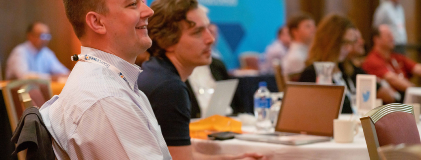 Side View Of People In Audience Reacting And Smiling At Speaker