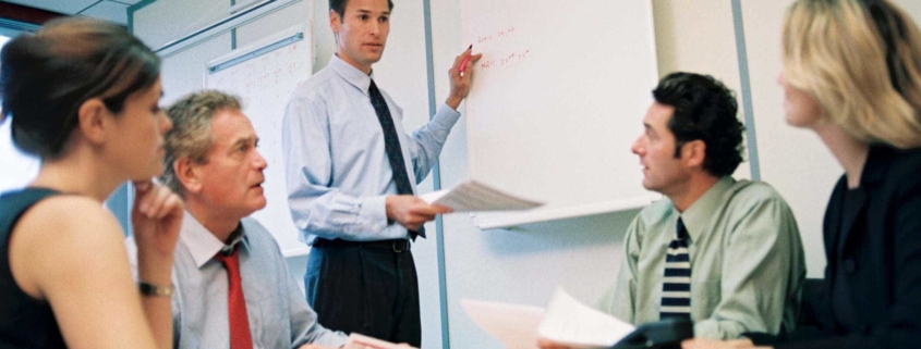 Man addressing four employees in a room