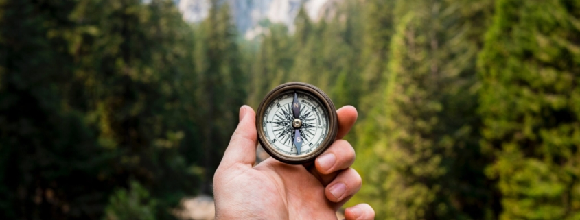 Man holding compass in the woods