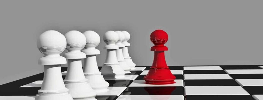 Image of chess board with various white pieces and one red piece