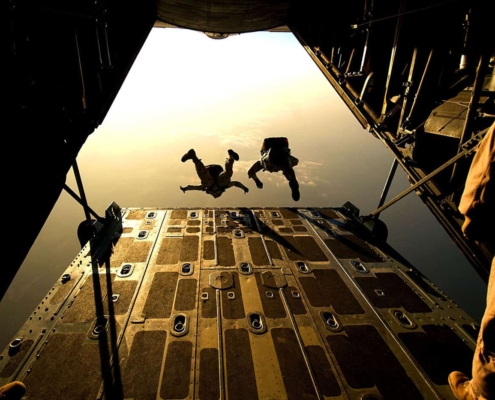 Two people jumping out of airplane with parachutes