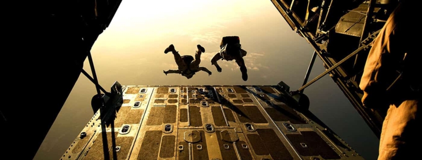 Two people jumping out of airplane with parachutes