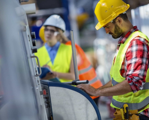 Two people in hard hats working in a factory