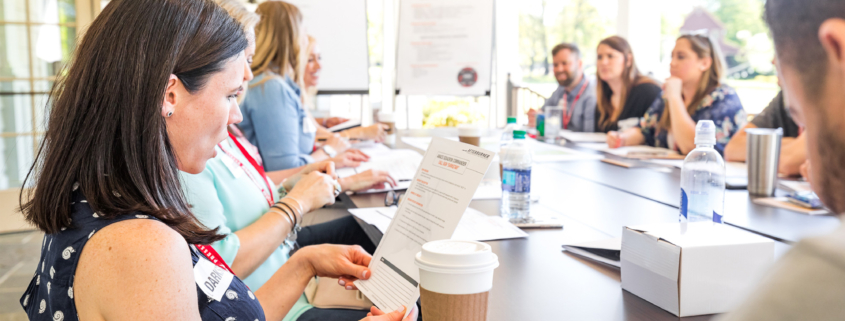 Side View Fo People At Afterburner Team Building Workshop Looking At Documents