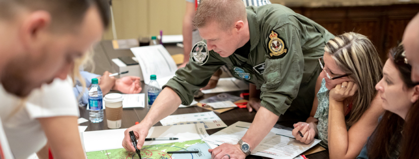 Side View Of Man Writing Something Down On Map, Strategy Meeting