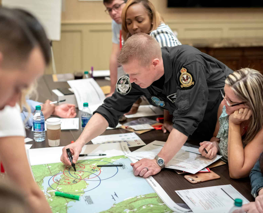 Side View Of Man Writing Something Down On Map Strategy Meeting Black Suit