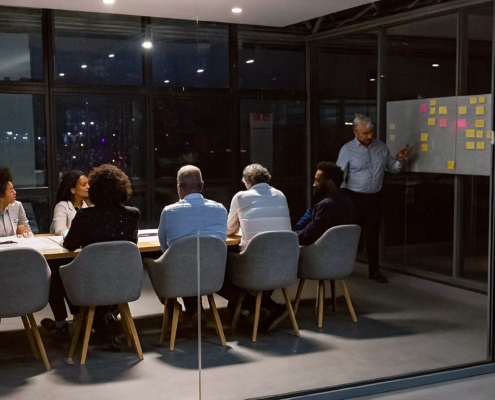 Leader facilitating a leadership debriefing workshop to analyze team performance on a whiteboard.